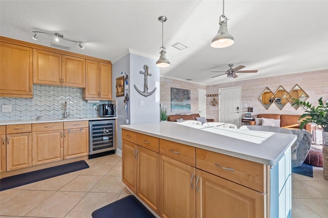 kitchen featuring sink, hanging light fixtures, beverage cooler, light tile patterned flooring, and ornamental molding