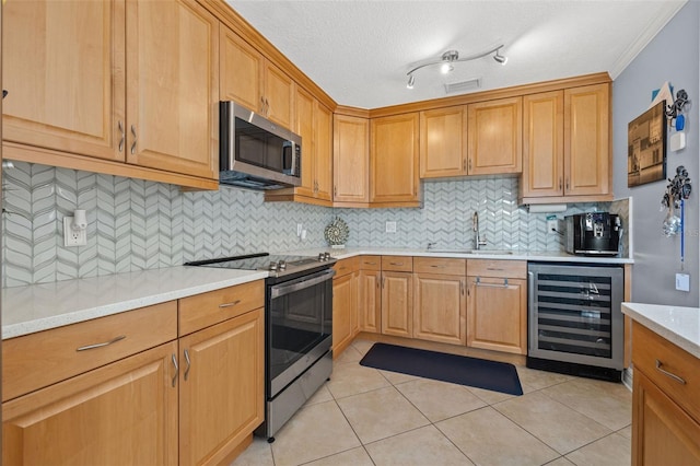 kitchen featuring a textured ceiling, stainless steel appliances, sink, light tile patterned floors, and wine cooler