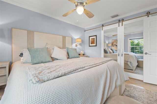 bedroom with a barn door, ceiling fan, ornamental molding, and light tile patterned flooring