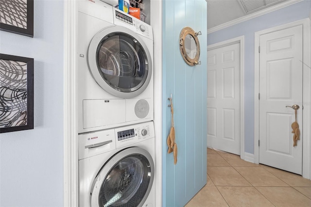 clothes washing area featuring stacked washer / dryer, crown molding, and light tile patterned floors