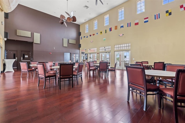 dining space with hardwood / wood-style floors, ceiling fan, a high ceiling, and french doors