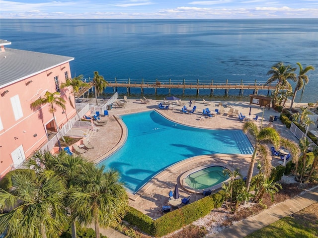 view of swimming pool featuring a water view, a hot tub, and a patio area