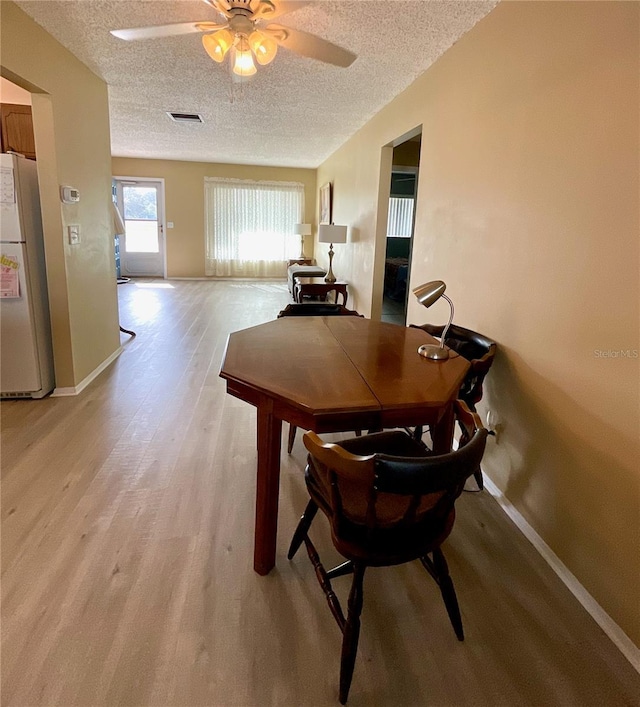 dining space featuring a textured ceiling, light hardwood / wood-style flooring, and ceiling fan