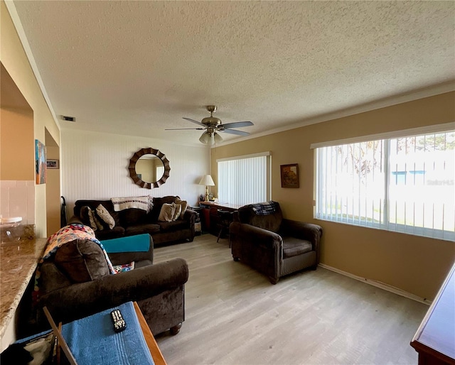 living room featuring ceiling fan, light hardwood / wood-style flooring, and a textured ceiling