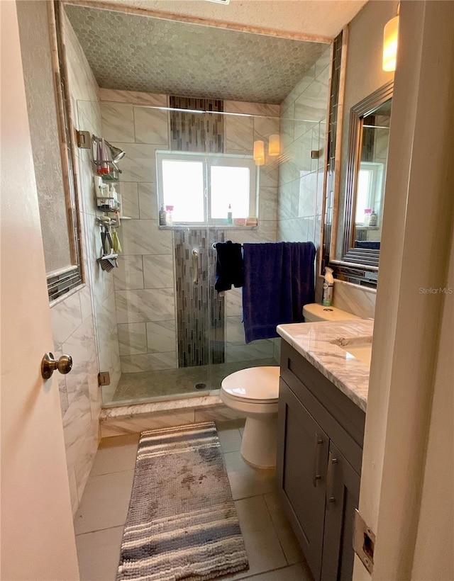 bathroom featuring toilet, vanity, tile patterned floors, and a shower with shower door