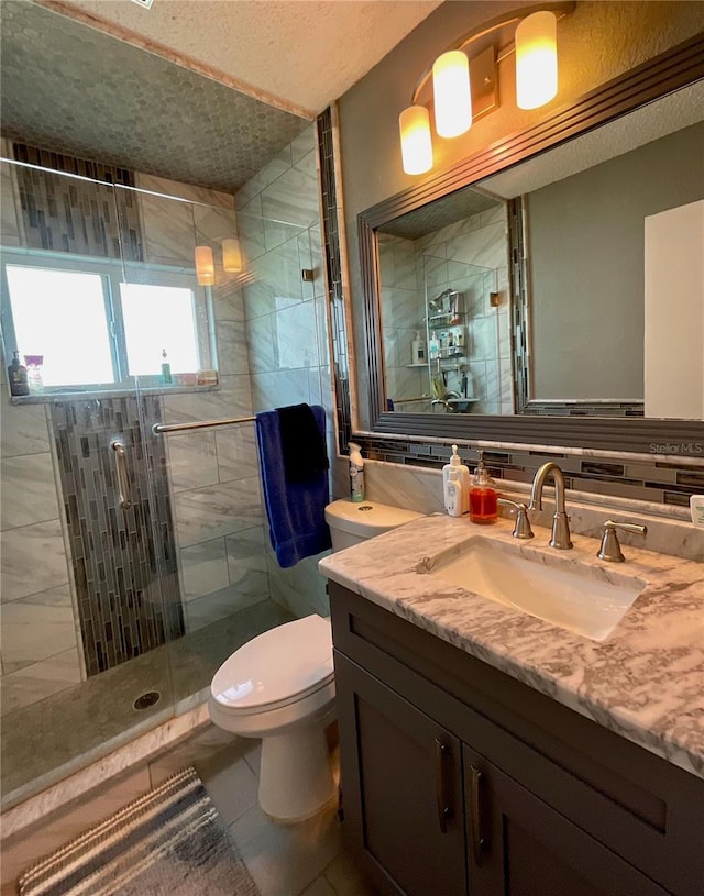 bathroom featuring tile patterned flooring, vanity, toilet, and walk in shower