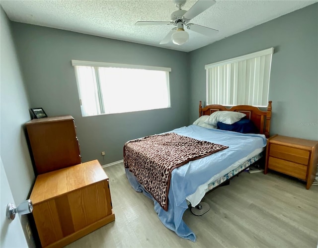 bedroom featuring a textured ceiling, light hardwood / wood-style floors, and ceiling fan