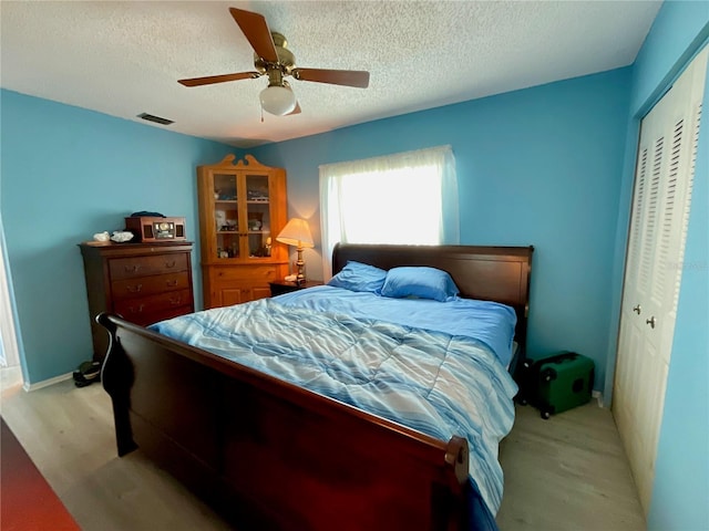 bedroom with light wood-type flooring, a textured ceiling, a closet, and ceiling fan