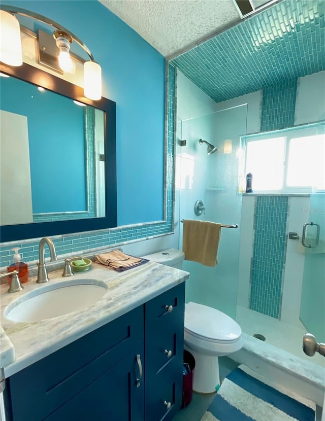 bathroom with tasteful backsplash, toilet, vanity, and tiled shower