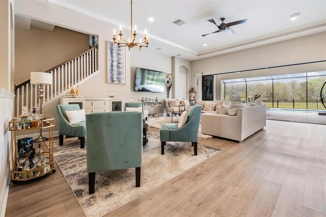 living room featuring ceiling fan with notable chandelier, light hardwood / wood-style floors, and crown molding