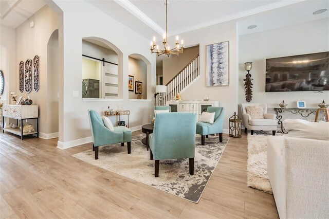 interior space featuring a barn door, ornamental molding, light hardwood / wood-style flooring, and an inviting chandelier