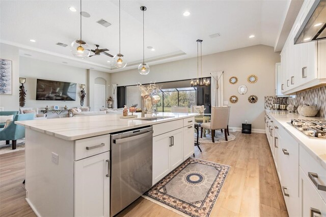 kitchen featuring white cabinetry, hanging light fixtures, a center island with sink, ceiling fan with notable chandelier, and appliances with stainless steel finishes