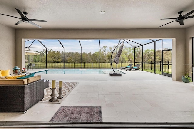 view of pool featuring glass enclosure, ceiling fan, and a patio area