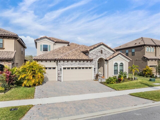 mediterranean / spanish-style home featuring a garage and a front lawn