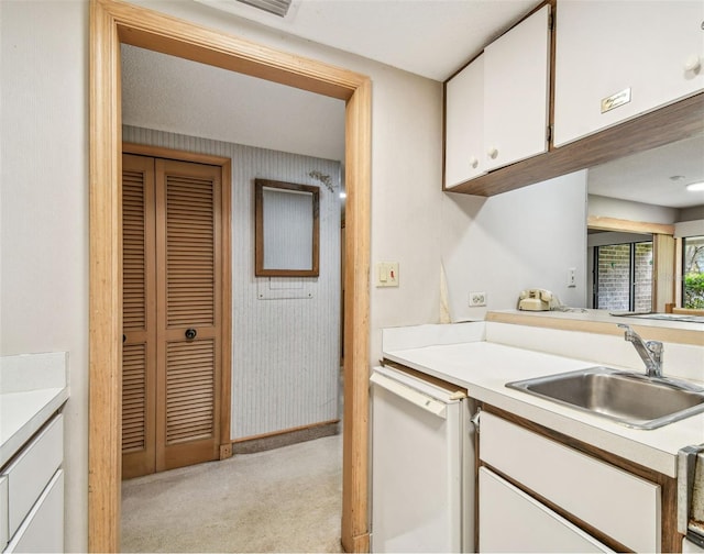 kitchen with sink, white cabinets, dishwasher, and light carpet