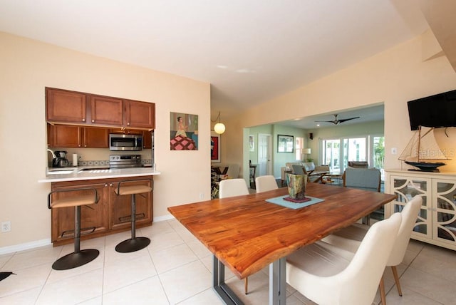 dining room featuring ceiling fan, light tile patterned flooring, and lofted ceiling