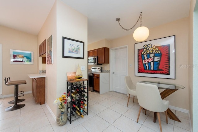 kitchen with light tile patterned flooring, hanging light fixtures, and appliances with stainless steel finishes