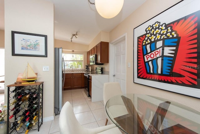 dining area featuring sink, light tile patterned flooring, and lofted ceiling