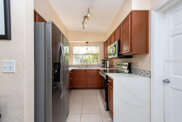 kitchen featuring track lighting, sink, hanging light fixtures, light tile patterned floors, and appliances with stainless steel finishes