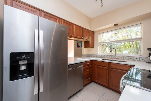 kitchen with pendant lighting, sink, decorative backsplash, light tile patterned flooring, and stainless steel appliances