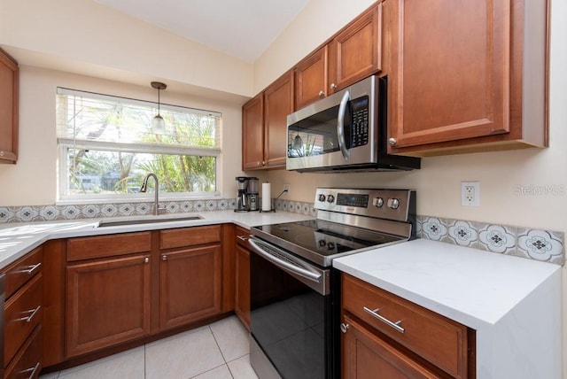 kitchen with sink, light tile patterned floors, hanging light fixtures, and appliances with stainless steel finishes