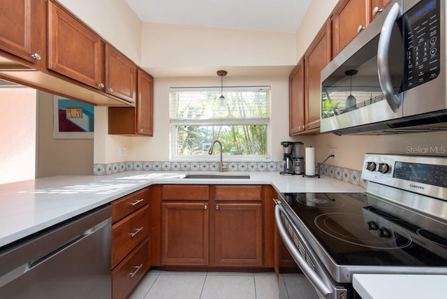 kitchen with hanging light fixtures, sink, light tile patterned floors, kitchen peninsula, and stainless steel appliances