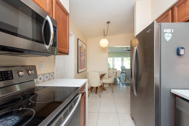 kitchen with light tile patterned floors, stainless steel appliances, hanging light fixtures, and ceiling fan