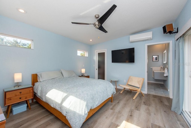 bedroom featuring ensuite bath, vaulted ceiling, ceiling fan, a wall unit AC, and light hardwood / wood-style floors