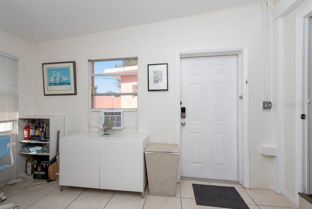 clothes washing area with cooling unit, light tile patterned flooring, and a healthy amount of sunlight