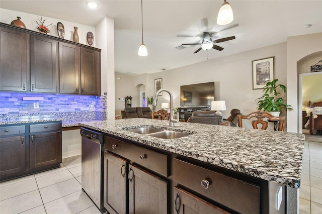 kitchen featuring stainless steel dishwasher, sink, light stone counters, and dark brown cabinetry