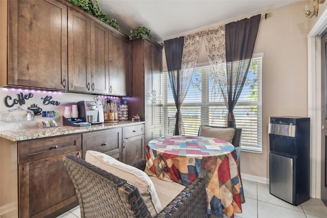 kitchen with light stone counters, light tile patterned floors, and dark brown cabinets