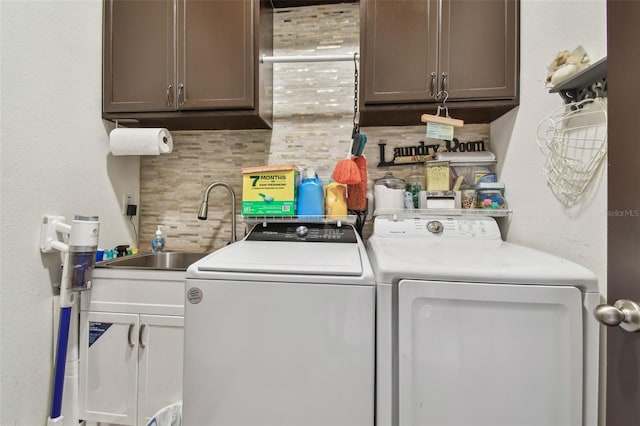 clothes washing area with washer and dryer, cabinets, and sink