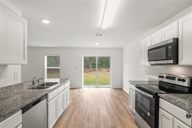 kitchen featuring white cabinets, sink, light stone countertops, a textured ceiling, and stainless steel appliances