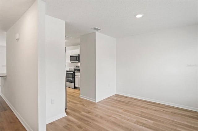 hall featuring light hardwood / wood-style floors and a textured ceiling