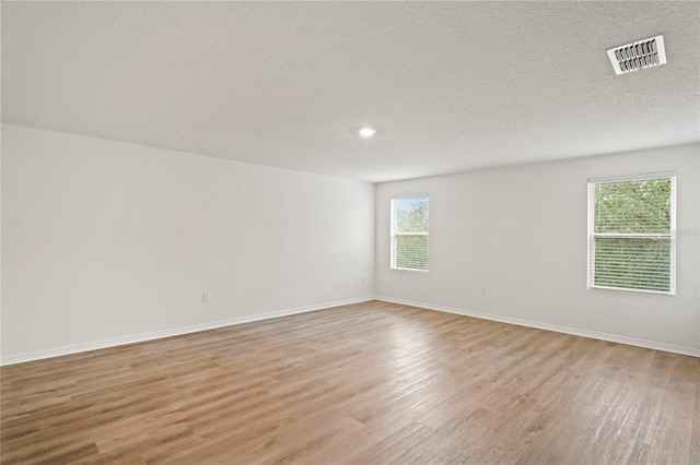 spare room with a textured ceiling and light hardwood / wood-style floors