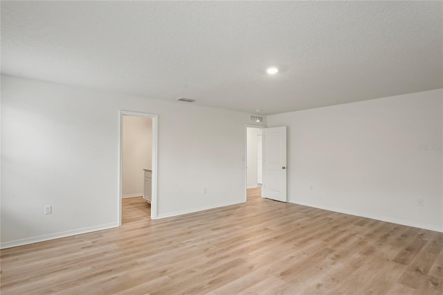 spare room with a textured ceiling and light hardwood / wood-style floors