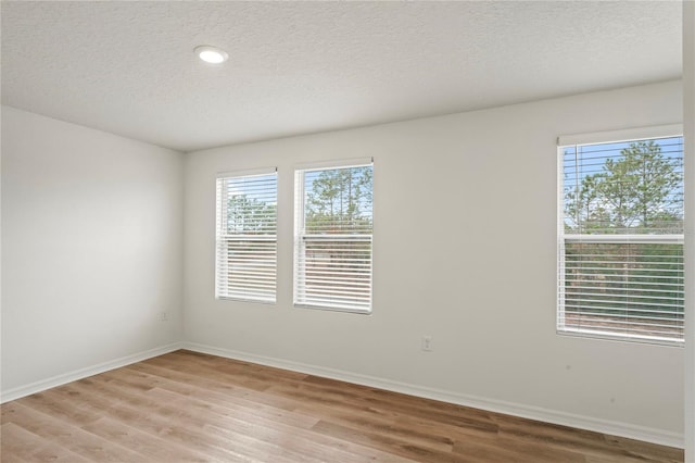 spare room featuring light wood-type flooring and a textured ceiling