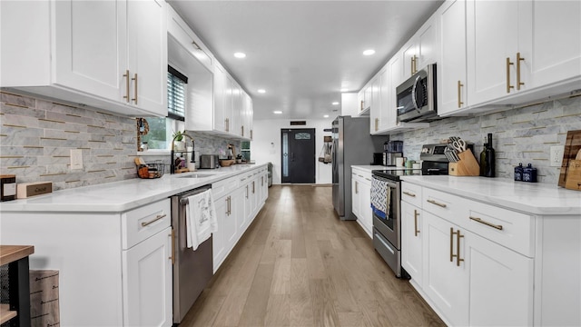 kitchen featuring sink, white cabinets, decorative backsplash, light hardwood / wood-style floors, and stainless steel appliances