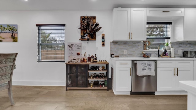 kitchen with sink, white cabinetry, light hardwood / wood-style flooring, dishwasher, and decorative backsplash