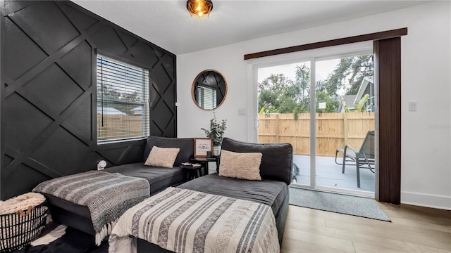 bedroom with multiple windows, access to exterior, and light hardwood / wood-style floors