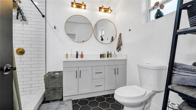 bathroom with tile patterned flooring, vanity, a tile shower, and toilet