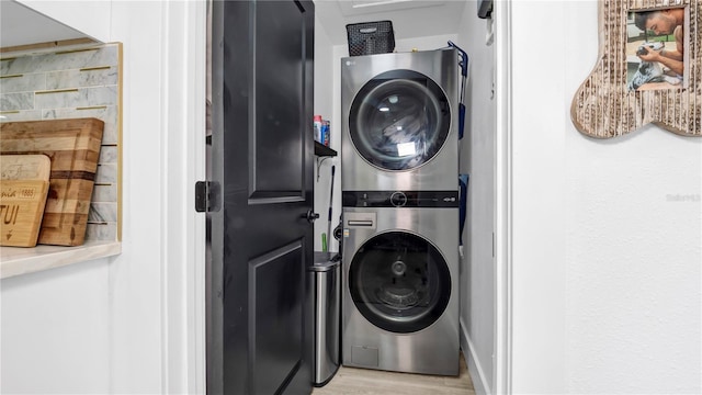 laundry area featuring stacked washer and clothes dryer and light wood-type flooring