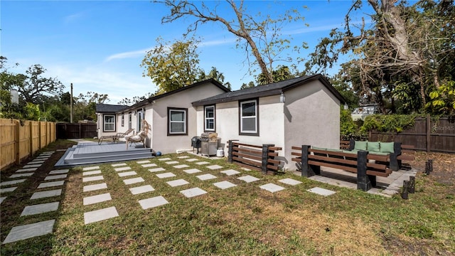 back of property with an outdoor living space, a wooden deck, and a lawn