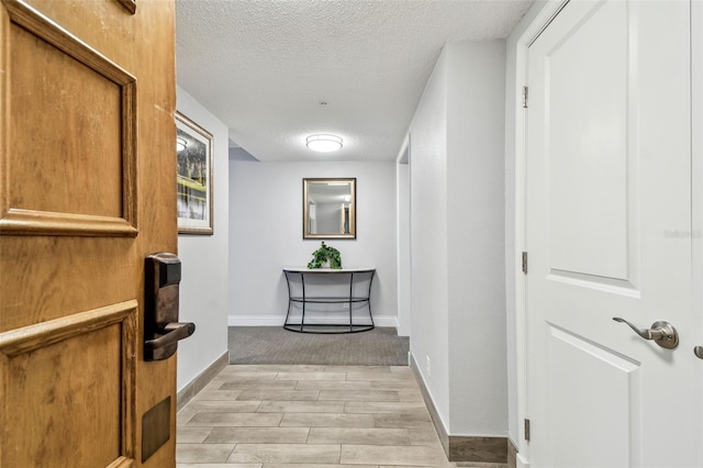 hallway with a textured ceiling and light hardwood / wood-style floors