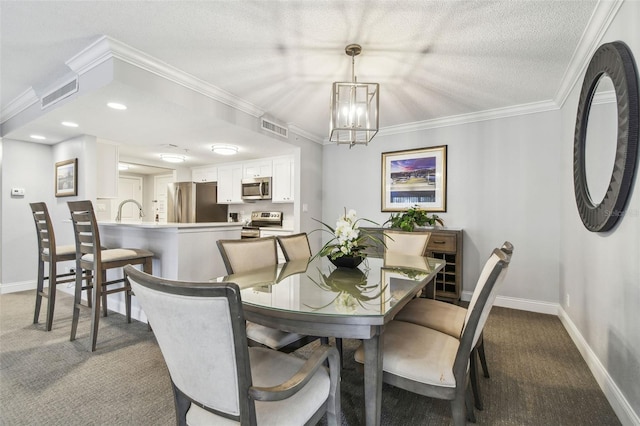 carpeted dining space with a chandelier, a textured ceiling, ornamental molding, and sink