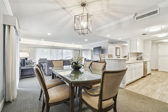 dining room featuring sink, a chandelier, a textured ceiling, and ornamental molding