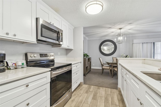 kitchen featuring pendant lighting, white cabinets, ornamental molding, a textured ceiling, and appliances with stainless steel finishes