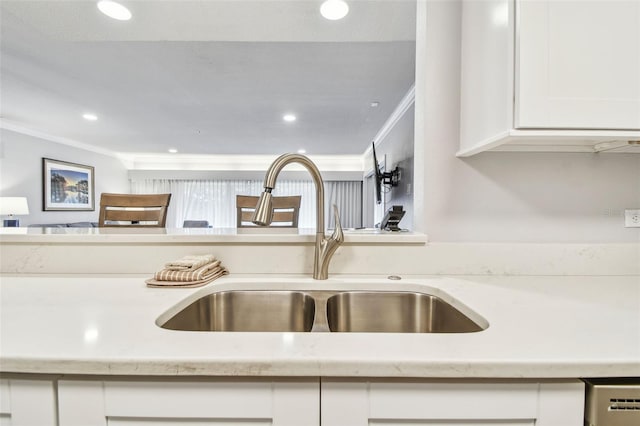 interior details featuring white cabinets, light stone countertops, crown molding, and sink