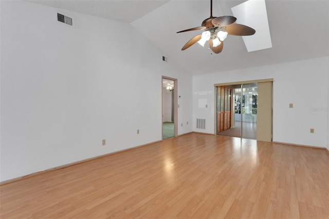 empty room featuring ceiling fan, vaulted ceiling with skylight, and light wood-type flooring