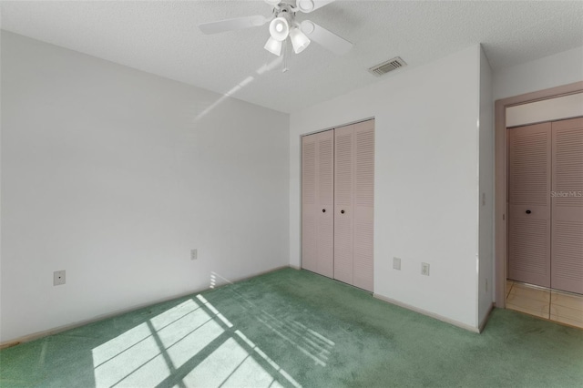 unfurnished bedroom featuring ceiling fan, carpet floors, a textured ceiling, and a closet